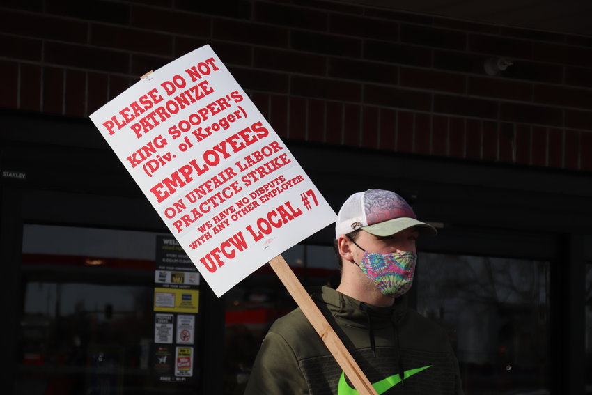 A striker outside a Littleton King Soopers store holds a sign urging people to shop elsewhere while workers strike for better wages and conditions.